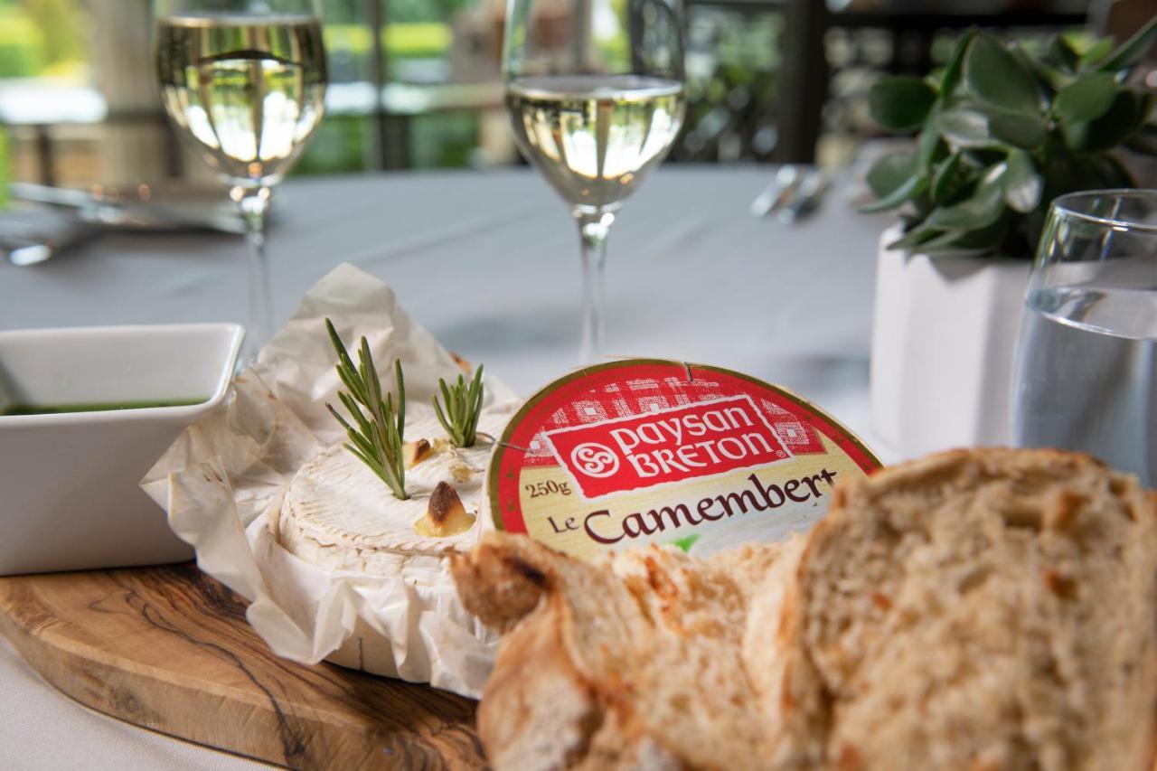 맥도날드 배스 스파 호텔 바스 외부 사진 The photo features a dining setting that includes a wooden platter with a round Camembert cheese, garnished with fresh rosemary sprigs. Nearby, there is a serving of bread, likely sliced, and a small bowl, potentially for dipping or spreading. In the