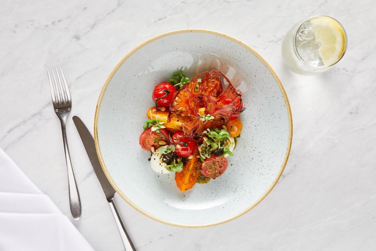 맥도날드 배스 스파 호텔 바스 외부 사진 The photo shows a beautifully arranged plate of food. The dish features a mix of colorful ingredients, including roasted or grilled vegetables, likely bell peppers and tomatoes, along with fresh greens. There are also some circular slices of another 