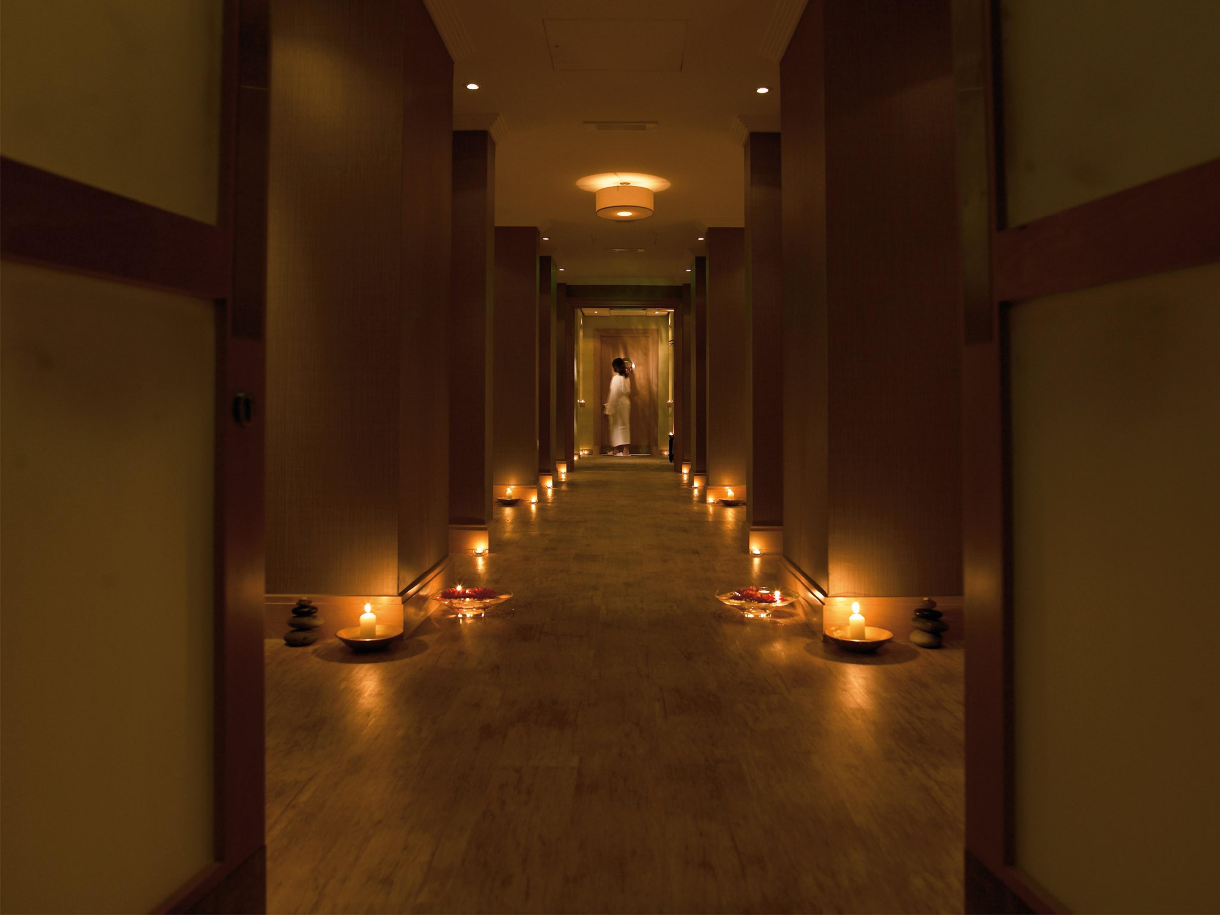 맥도날드 배스 스파 호텔 바스 외부 사진 The photo shows a dimly lit corridor lined with soft lighting. On both sides of the hallway, small candles are placed in bowls, creating a warm and inviting ambiance. At the end of the corridor, there appears to be a person standing, possibly prepari