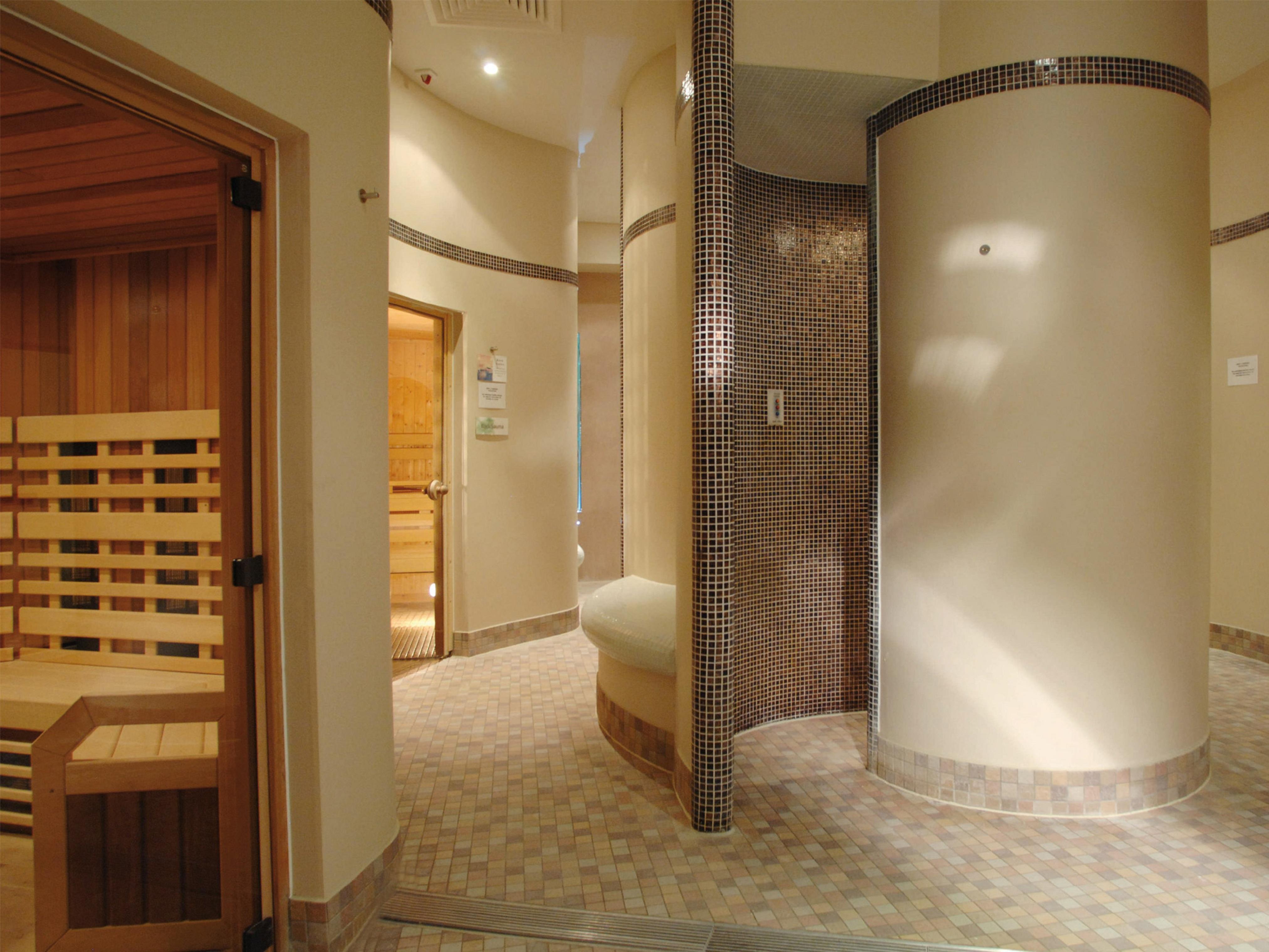 맥도날드 배스 스파 호텔 바스 외부 사진 The photo shows a contemporary spa area featuring a sauna and relaxation space. The interior has smooth, rounded walls and tiled surfaces, creating a calming atmosphere. On one side, there's a wooden sauna with slatted seating. Nearby, a curved wall 