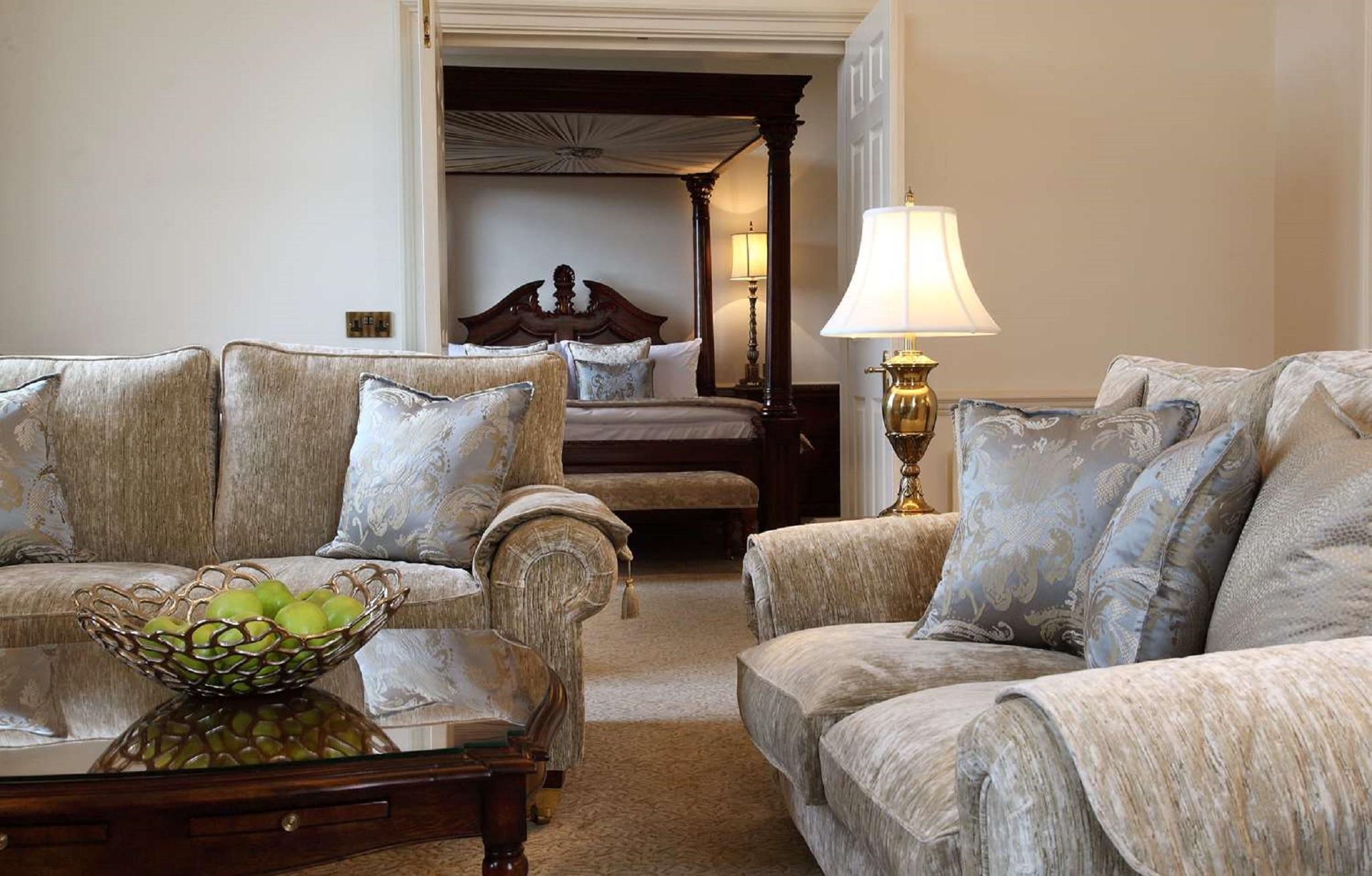 맥도날드 배스 스파 호텔 바스 외부 사진 The photo shows a cozy living space with elegant furnishings. On the left, there is a sofa with plush cushions and a stylish armchair, both in a soft, light-colored fabric. In the center, there is a decorative glass table with a bowl containing what 