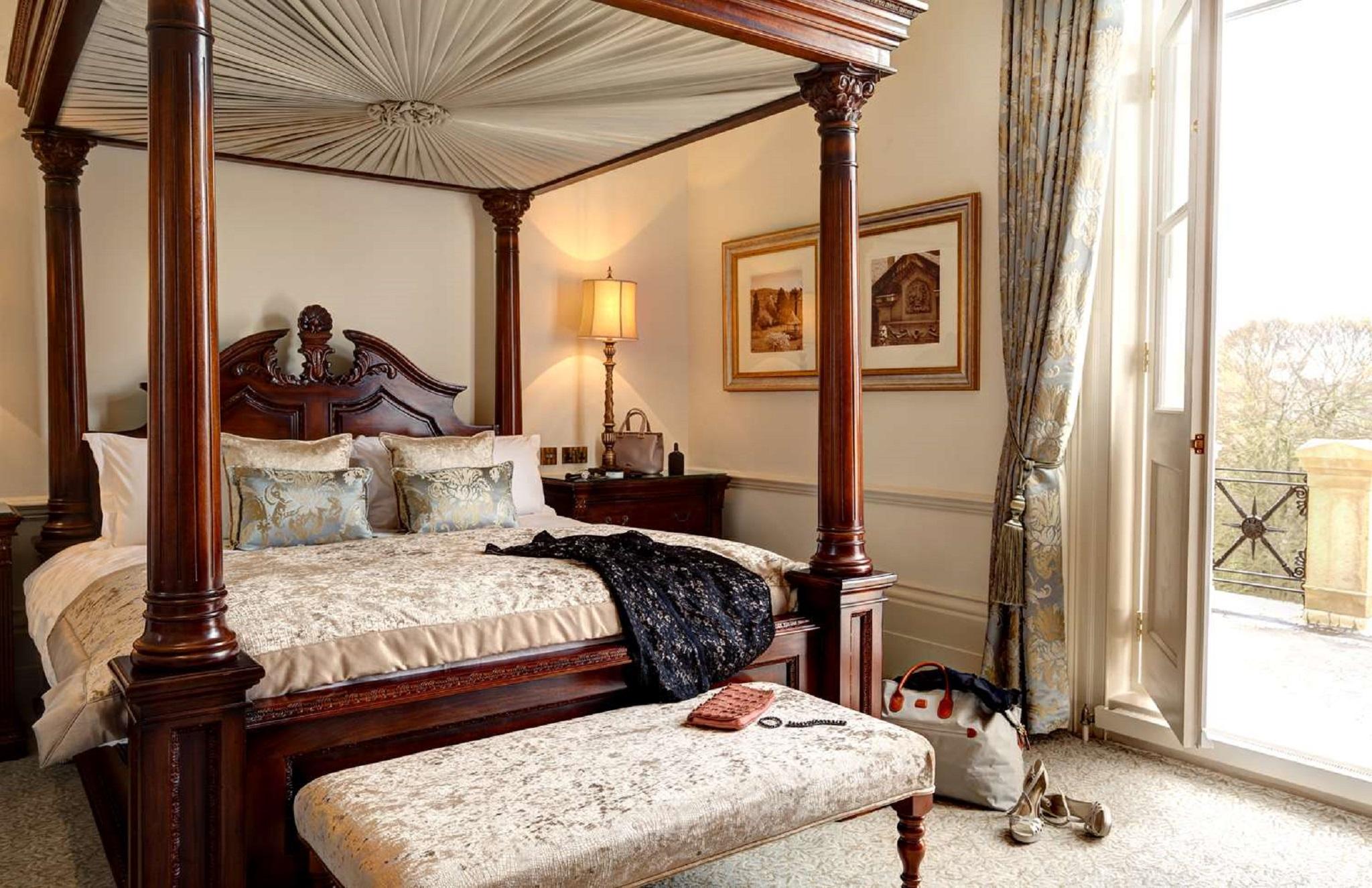 맥도날드 배스 스파 호텔 바스 외부 사진 The photo depicts a beautifully designed bedroom featuring a four-poster bed with a decorative canopy. The bed is dressed with elegant bedding and several patterned pillows. Adjacent to the bed, there is a matching wooden nightstand with a stylish la