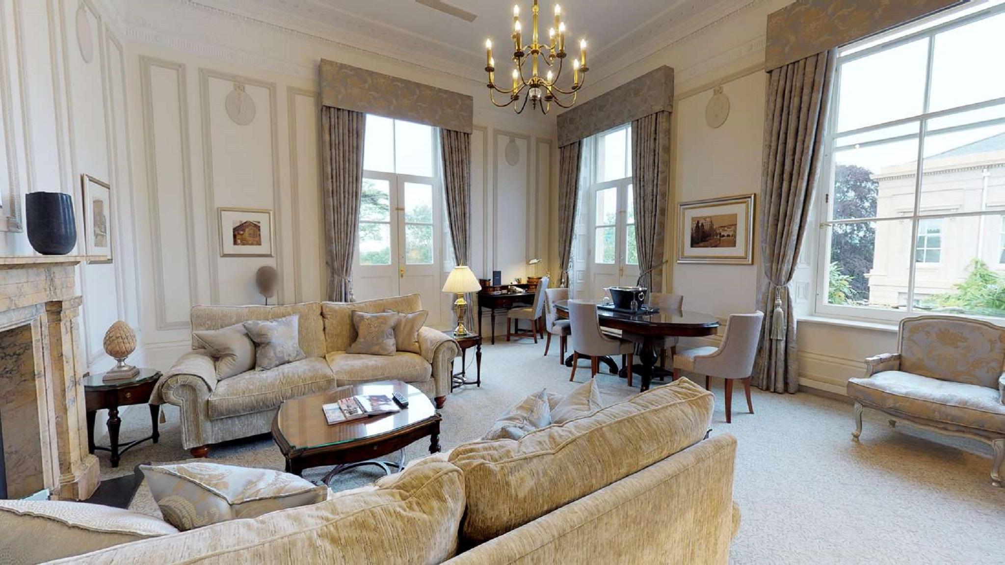 맥도날드 배스 스파 호텔 바스 외부 사진 The photo displays a spacious and elegantly furnished living room. It features plush sofas and armchairs arranged around a central coffee table, creating a cozy seating area. Large windows adorned with long curtains allow natural light to fill the ro