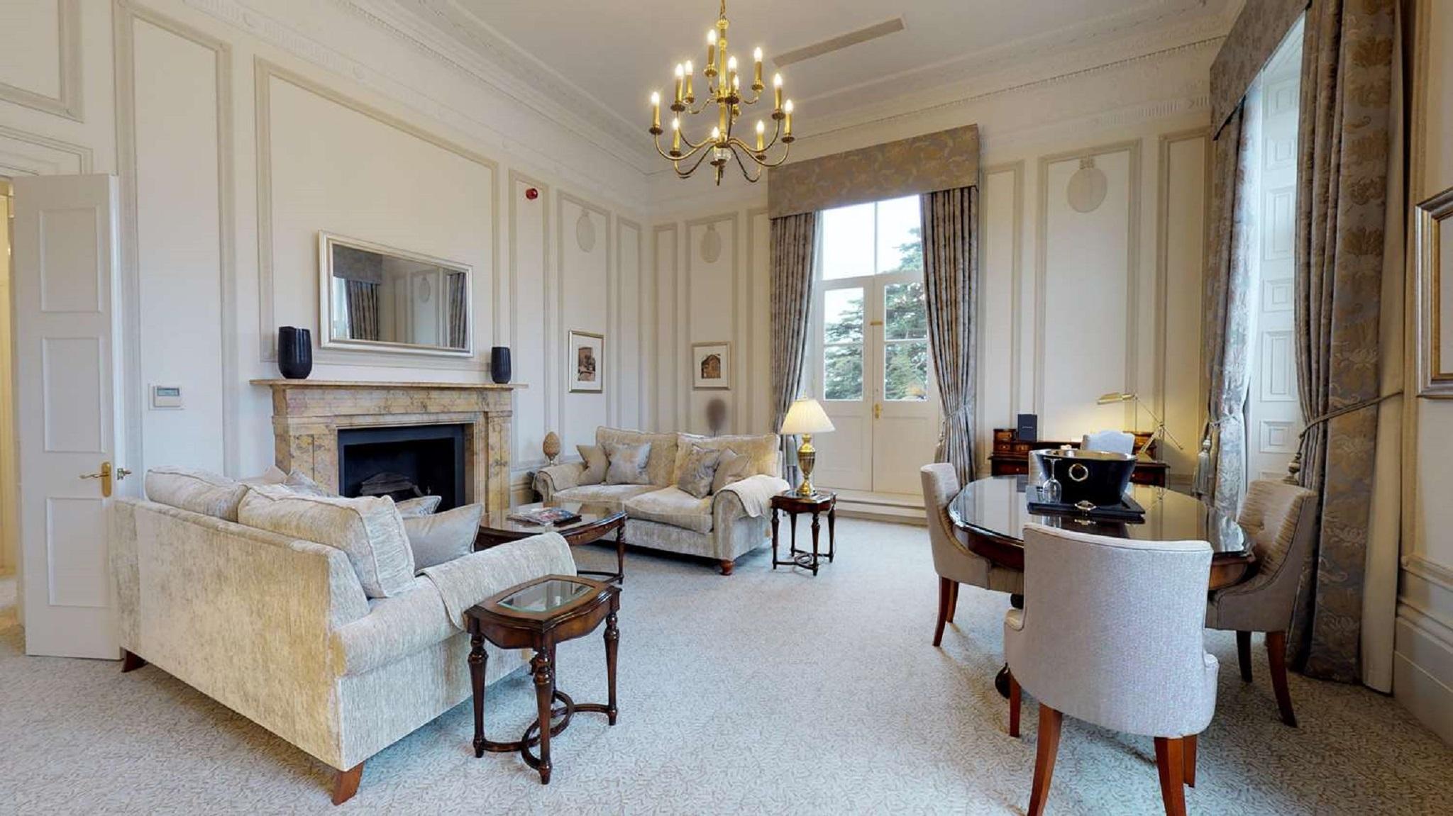 맥도날드 배스 스파 호텔 바스 외부 사진 The photo shows an elegant living room with a classic design. It features a large chandelier hanging from the ceiling, providing soft lighting. The walls are adorned with decorative moldings and have a light color. 

In the center, there are two plus