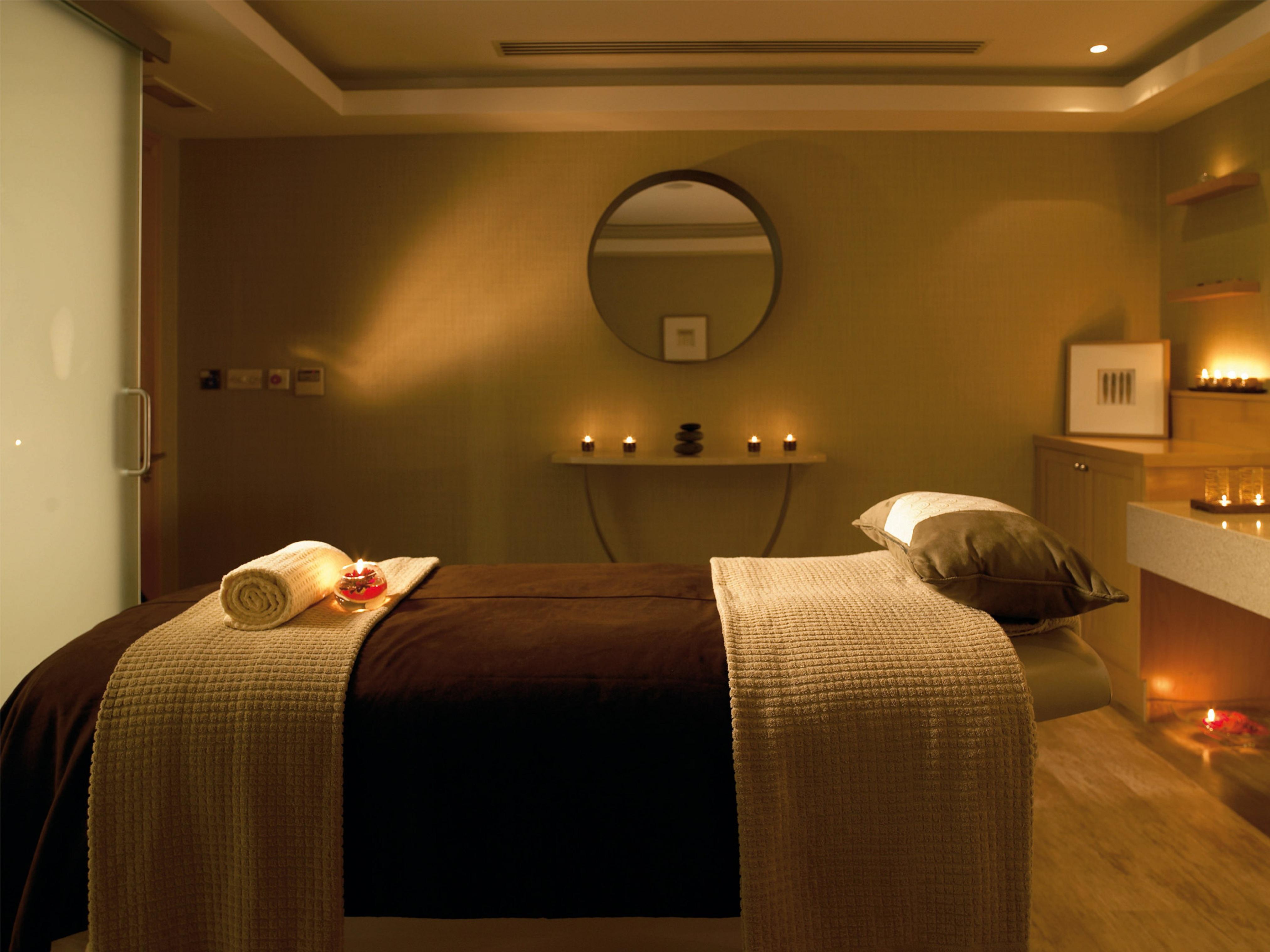 맥도날드 배스 스파 호텔 바스 외부 사진 The photo shows a serene spa room designed for relaxation and wellness. A comfortable massage table is centered in the room, covered with a soft, neutral-toned blanket. On the table, there is a rolled towel and a few decorative elements, possibly flo